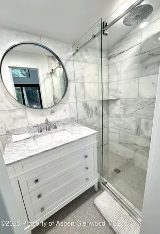 a bathroom with a granite countertop sink mirror and shower