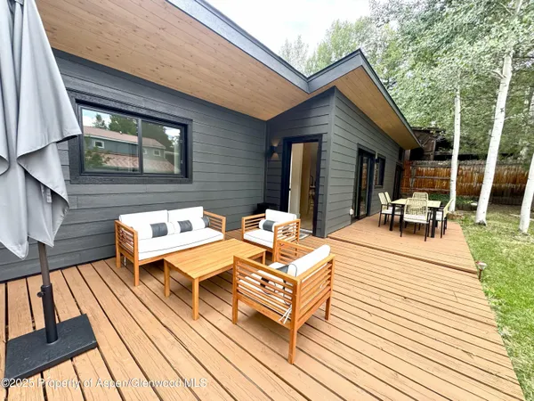 a view of a patio with couches table and chairs with wooden floor and fence