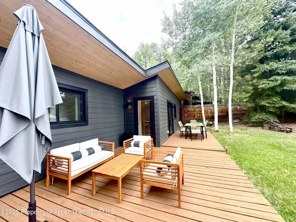 a view of a patio with table and chairs with wooden floor and fence