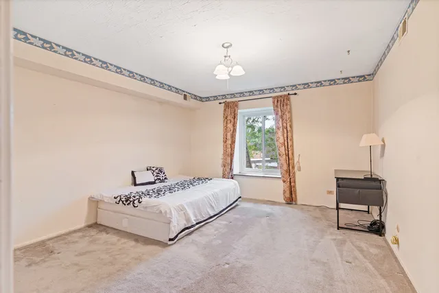 a bedroom with a bed chandelier and a window