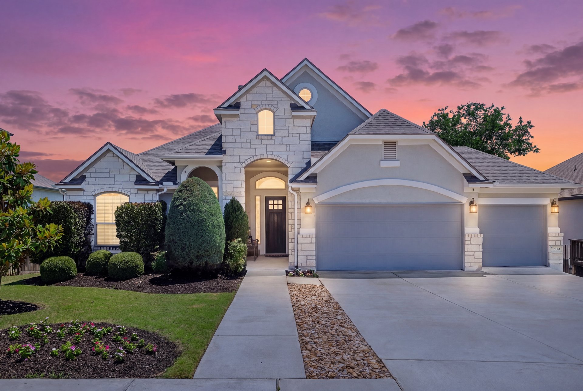 309 Rancho Sienna Loop Georgetown, TX 78628 - Photo 1 of 40 Stone and stucco exterior featuring a gabled roofline, arched entry, and a multi-car driveway with integrated gravel accents