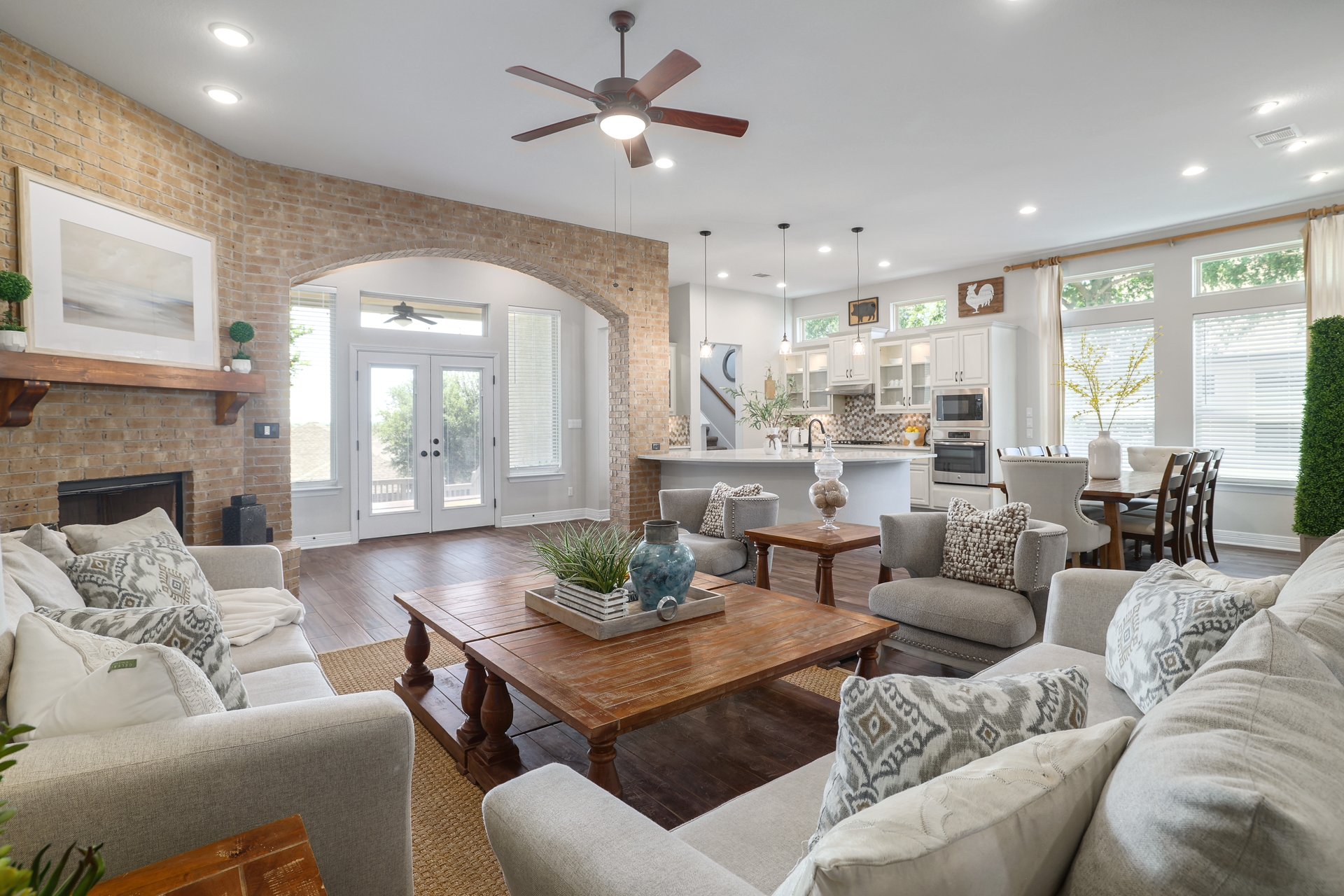 309 Rancho Sienna Loop Georgetown, TX 78628 - Photo 12 of 40 Open-concept living space featuring a brick-accented fireplace with a wood mantle, recessed lighting, and dark wood-finish flooring