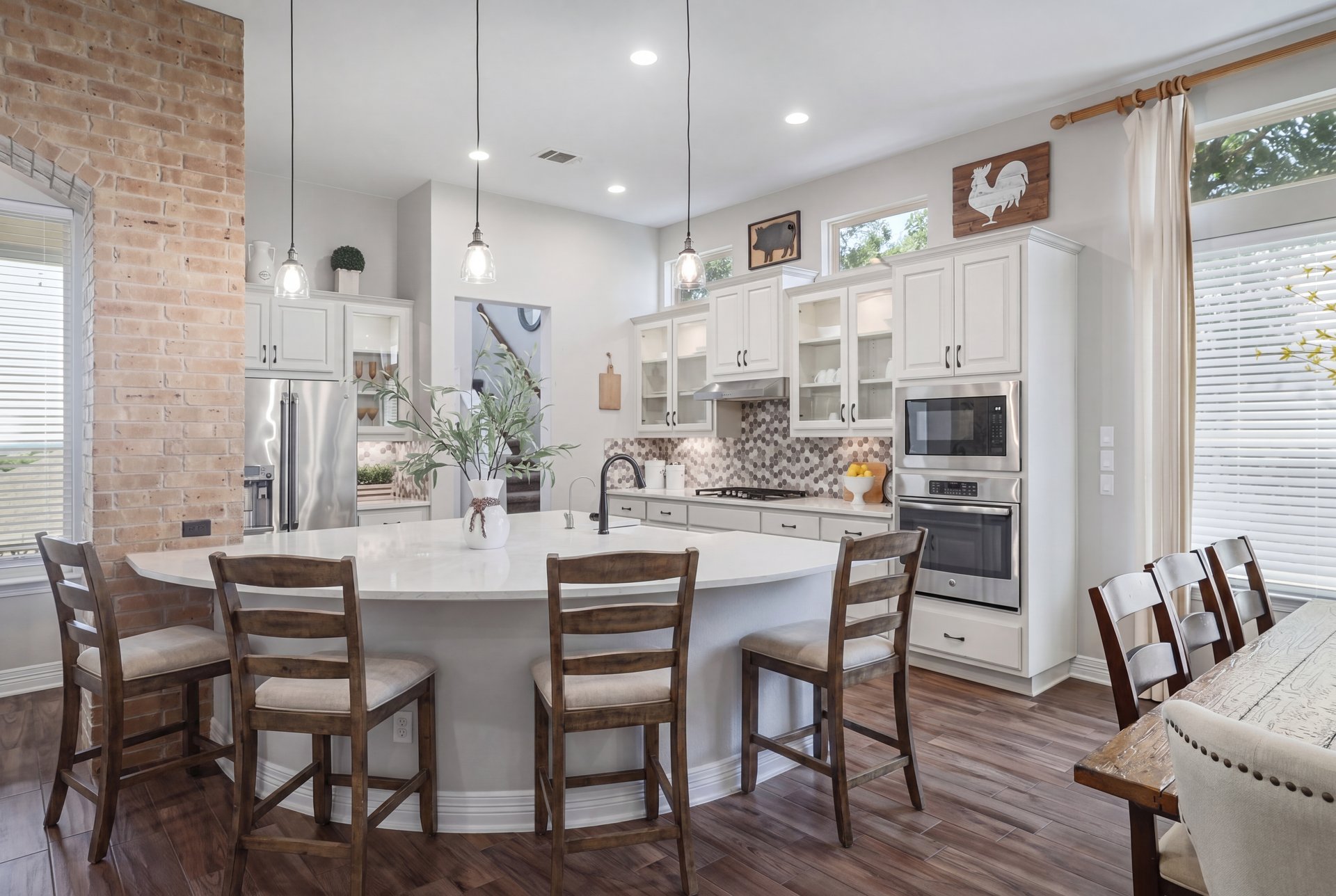 309 Rancho Sienna Loop Georgetown, TX 78628 - Photo 13 of 40 Spacious kitchen featuring a large oval island with seating, a patterned tile backsplash, stainless steel appliances, white cabinetry, and wood-finish flooring