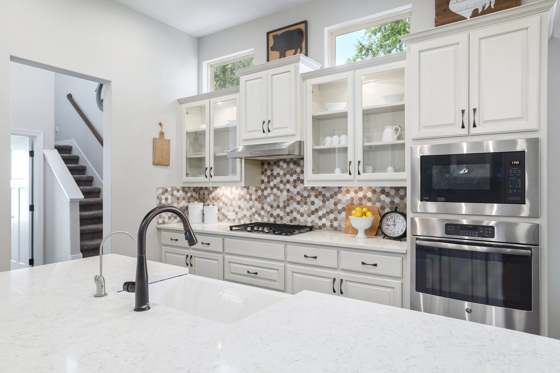309 Rancho Sienna Loop Georgetown, TX 78628 - Photo 16 of 40 Modern kitchen featuring white cabinetry with dark hardware, a hexagonal tile backsplash, stainless steel appliances, and a gas range