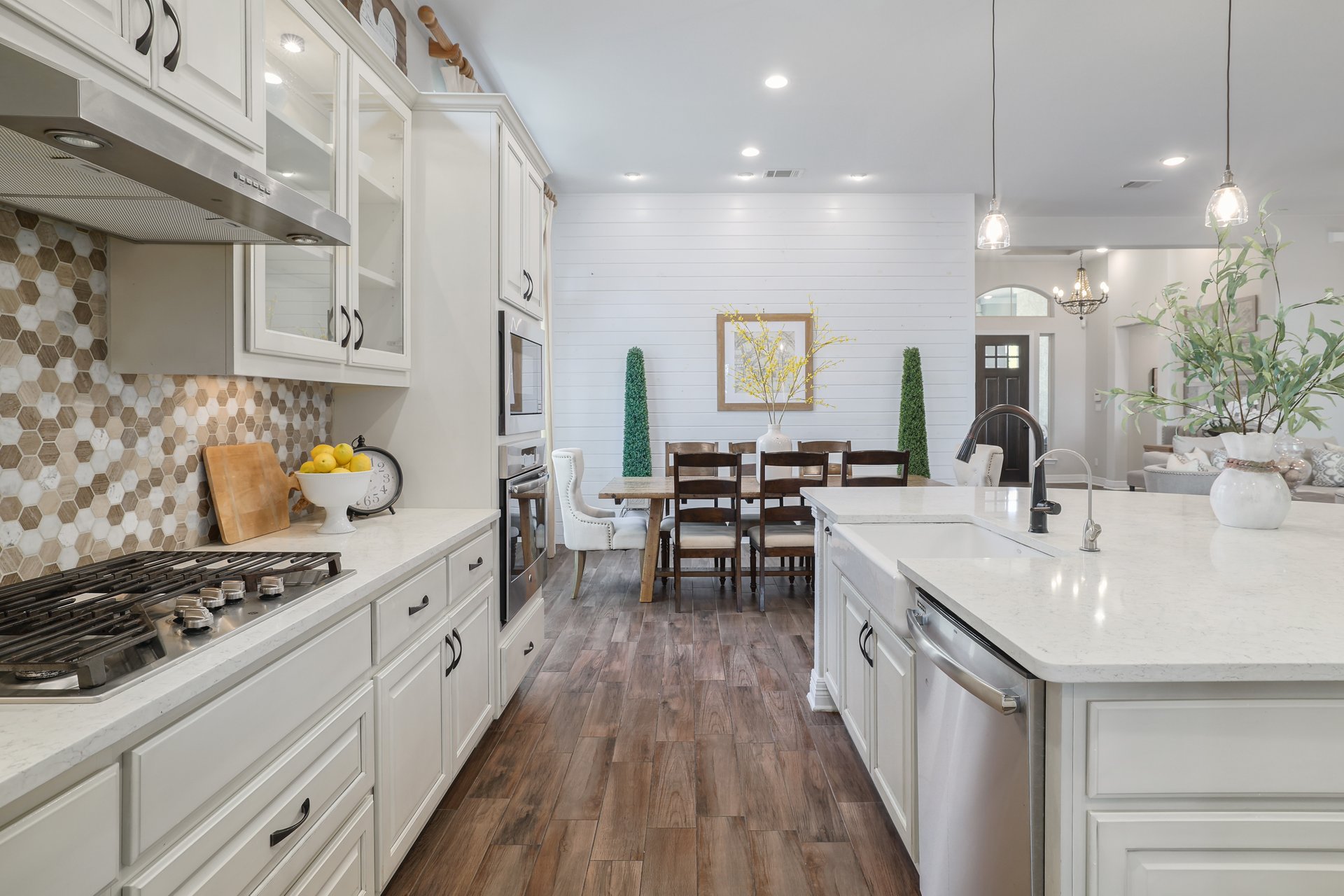 309 Rancho Sienna Loop Georgetown, TX 78628 - Photo 17 of 40 Gourmet kitchen featuring light cabinetry, a hexagonal tile backsplash, built-in stainless steel appliances, a center island with an undermount sink, and wood-finish flooring