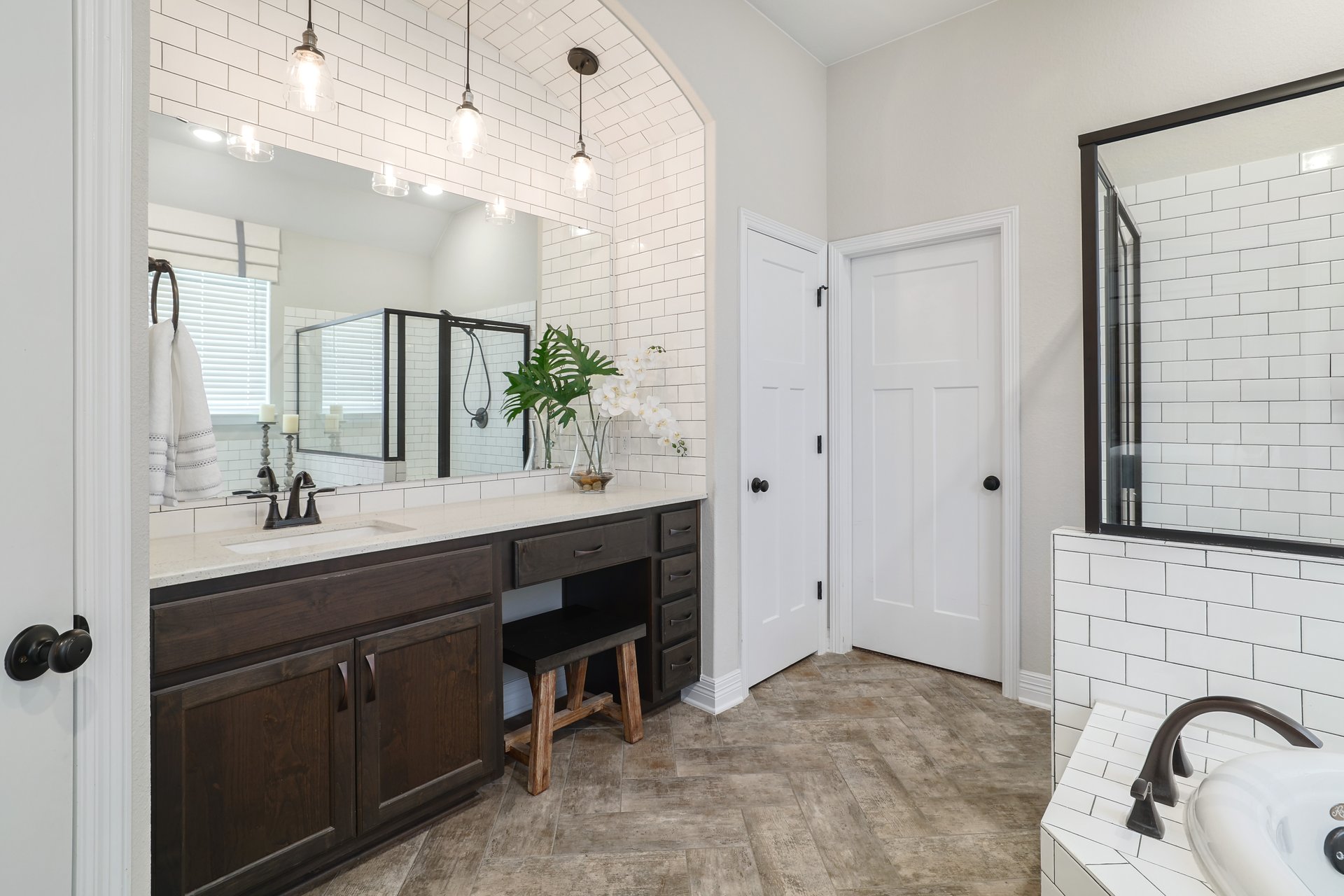 309 Rancho Sienna Loop Georgetown, TX 78628 - Photo 23 of 40 Bathroom featuring a dual-sink vanity with dark wood cabinetry and a light-toned countertop, set against a subway tile accent wall with three pendant lights