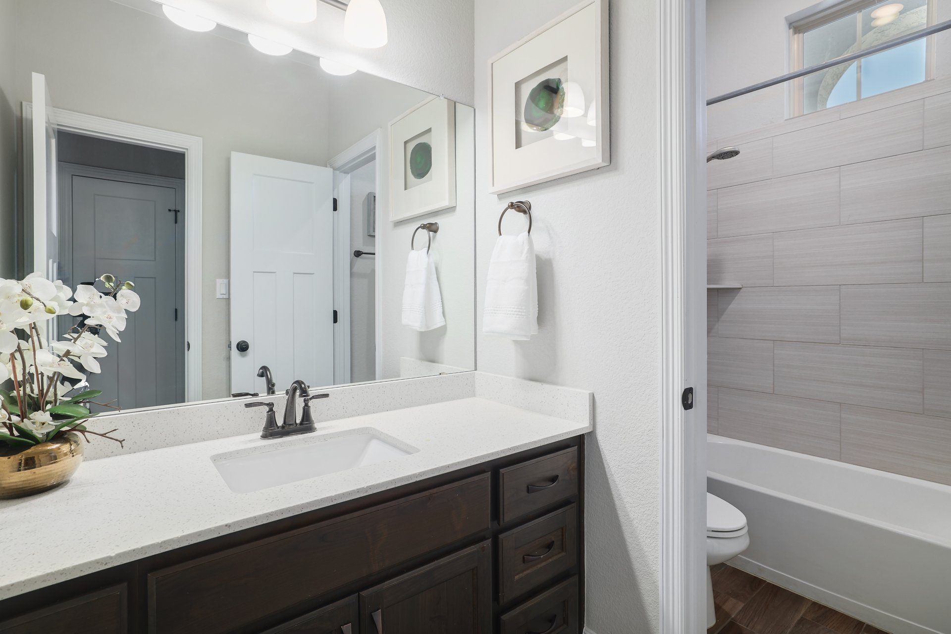 309 Rancho Sienna Loop Georgetown, TX 78628 - Photo 26 of 40 Bathroom vanity featuring a light-colored countertop with an undermount sink, dark wood-finish cabinetry, and a wide mirror