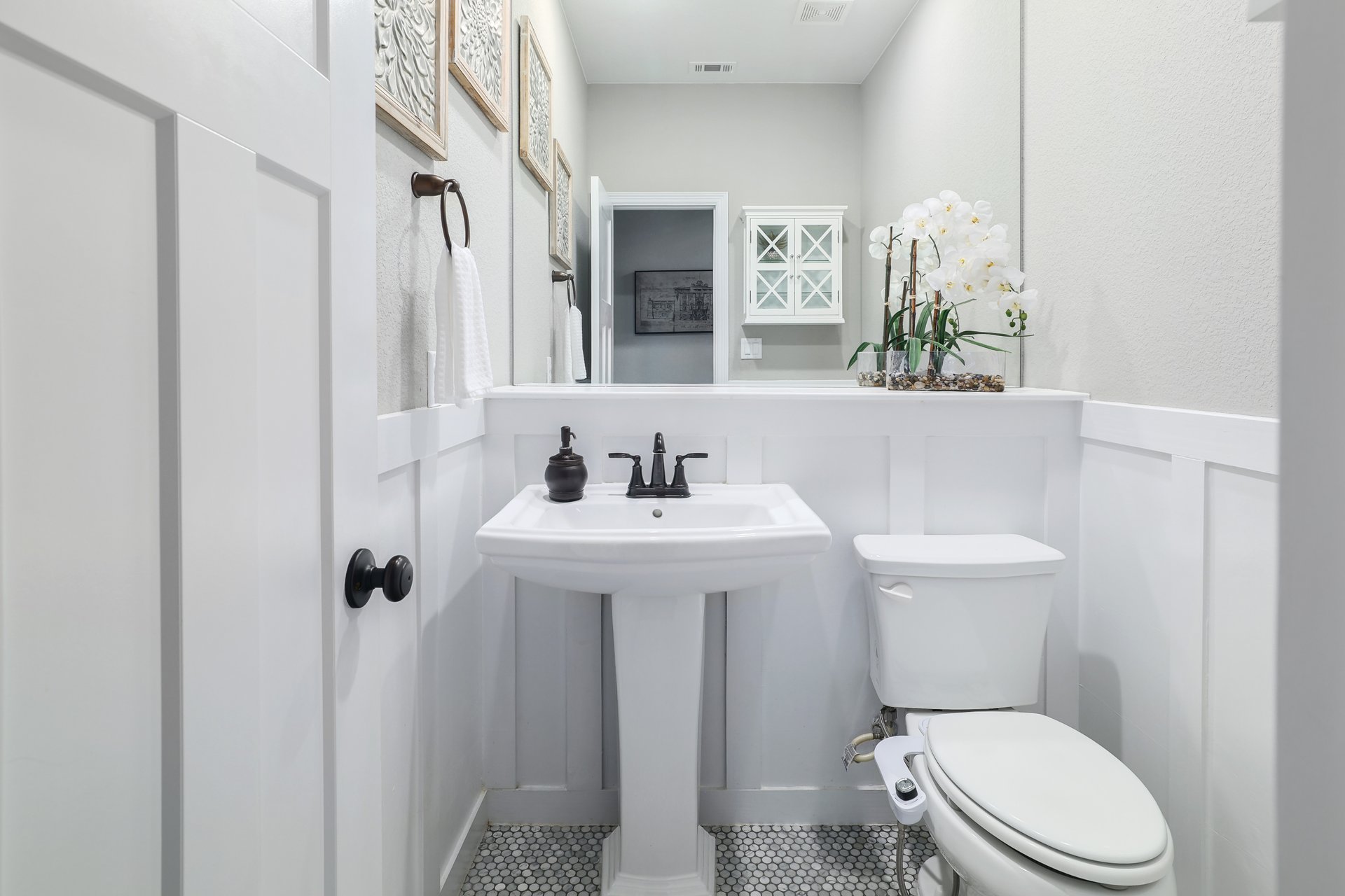 309 Rancho Sienna Loop Georgetown, TX 78628 - Photo 28 of 40 Pedestal sink with dark-finish faucet, white wainscoting, and hexagonal mosaic floor tiling