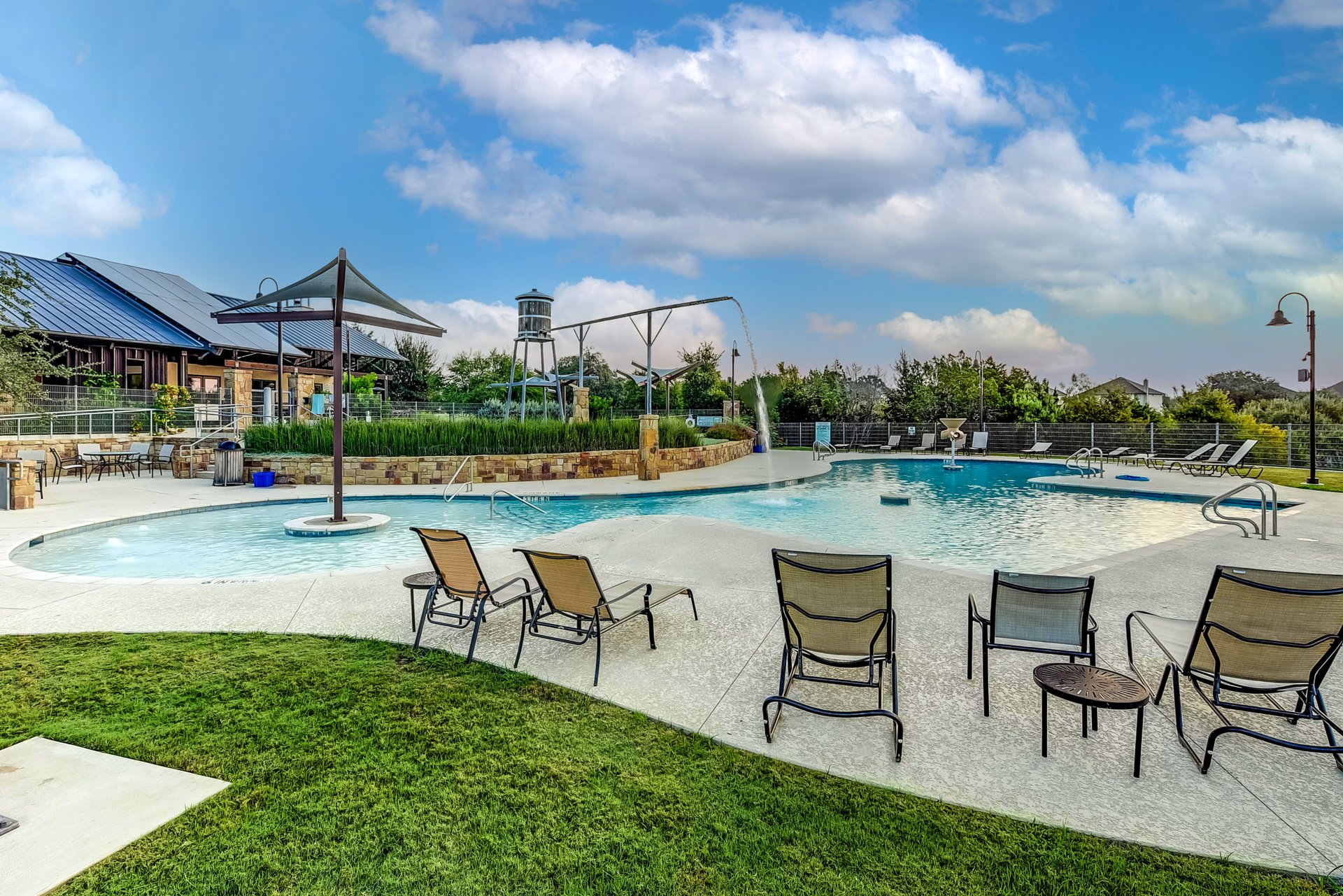 309 Rancho Sienna Loop Georgetown, TX 78628 - Photo 38 of 40 Community pool area featuring a curved leisure pool with a baja shelf, a separate lap pool, integrated water features, and a stone-accented pool house with an outdoor patio