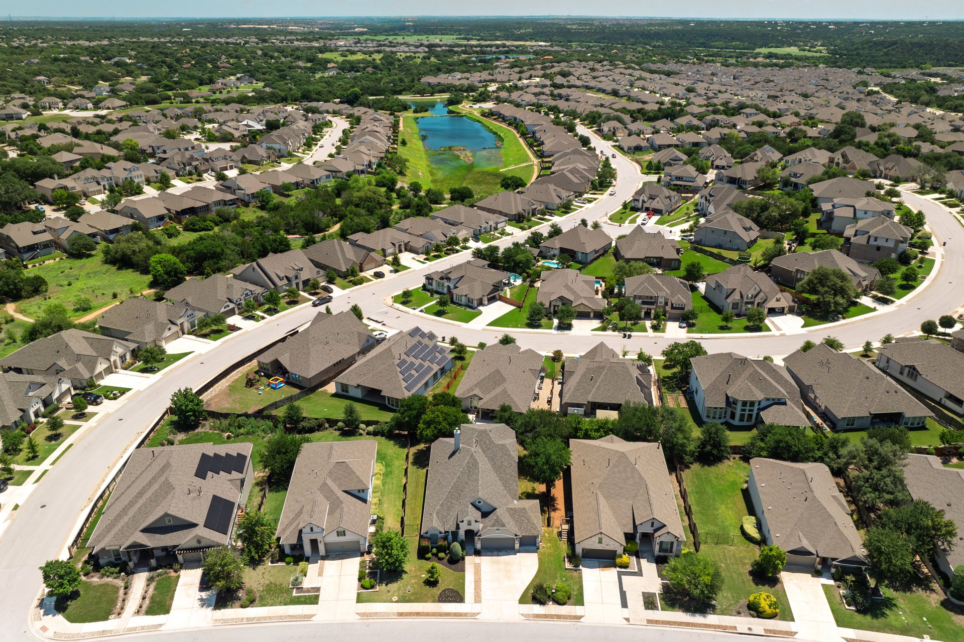 309 Rancho Sienna Loop Georgetown, TX 78628 - Photo 6 of 40 Expansive residential development featuring curving streets, numerous single-family homes with diverse architectural styles, mature trees, and a central pond feature
