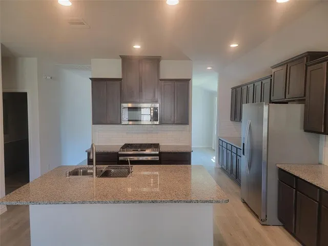 a kitchen with kitchen island granite countertop a refrigerator stove and sink