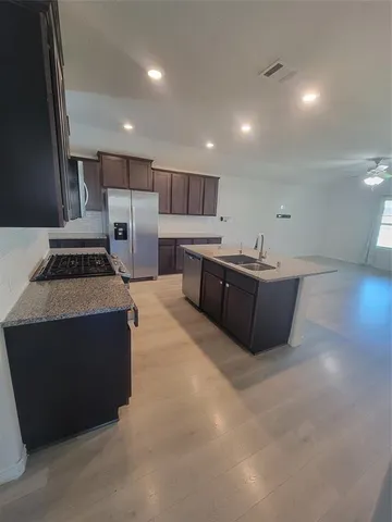 a kitchen with stainless steel appliances a sink a stove a refrigerator cabinets and a counter top space