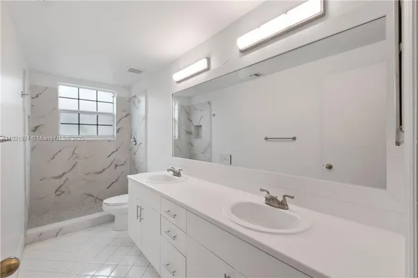 a bathroom with a double vanity sink toilet mirror and bathtub