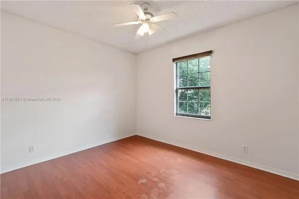 an empty room with a window and a fan