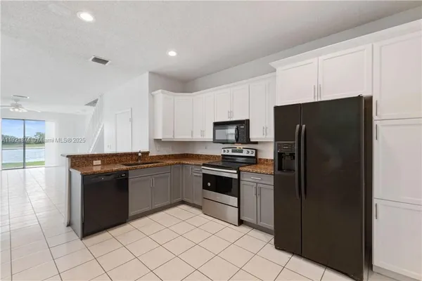 a kitchen with stainless steel appliances granite countertop a refrigerator and a stove top oven
