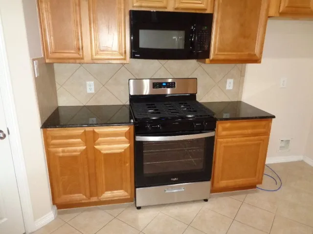 a kitchen with granite countertop white cabinets and stainless steel appliances