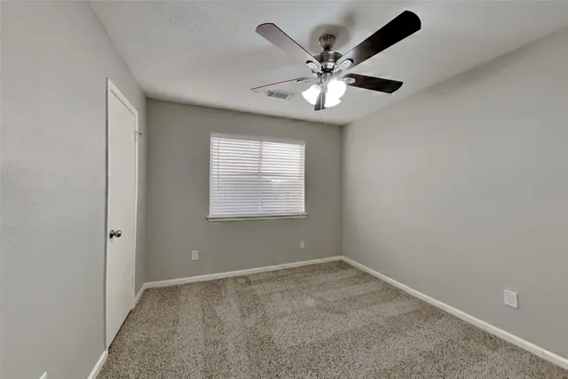 an empty room with a window and a fan