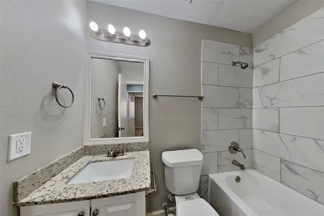 a bathroom with a granite countertop sink a toilet and bathtub
