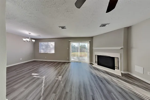 a view of an empty room with wooden floor fireplace and a window