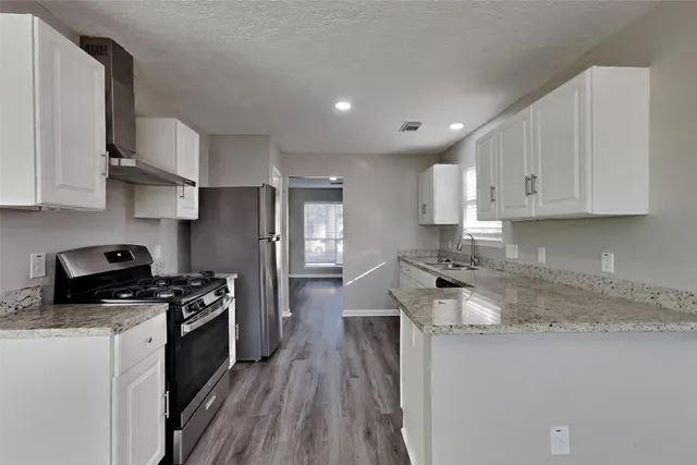 a kitchen with stainless steel appliances granite countertop a stove a sink and a refrigerator