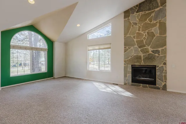 an empty room with windows and fireplace