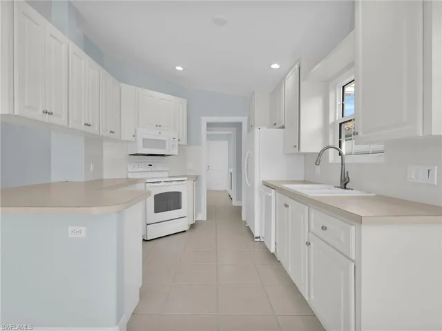 a kitchen with granite countertop white cabinets and white stainless steel appliances
