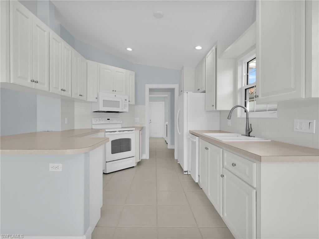 4231 Redonda Lane Naples, FL 34119 - Photo 12 of 42 a kitchen with granite countertop white cabinets and white stainless steel appliances