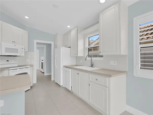 a kitchen with white cabinets and sink