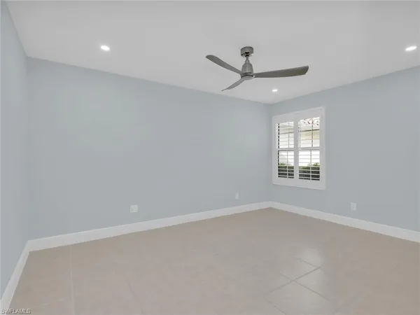 an empty room with ceiling fan and window