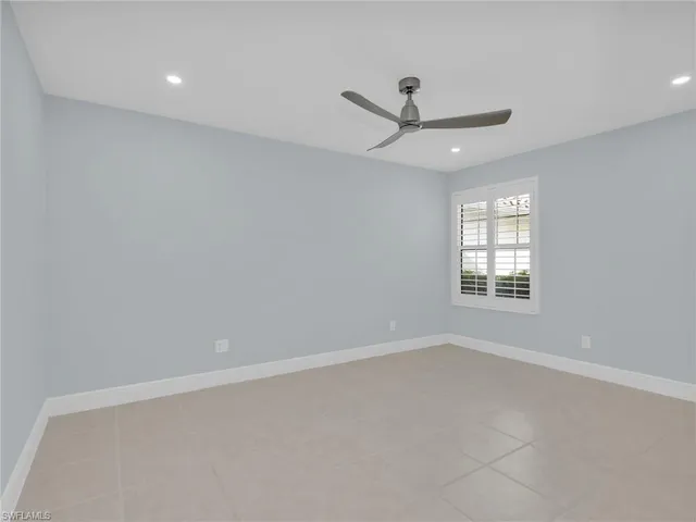 an empty room with ceiling fan and window