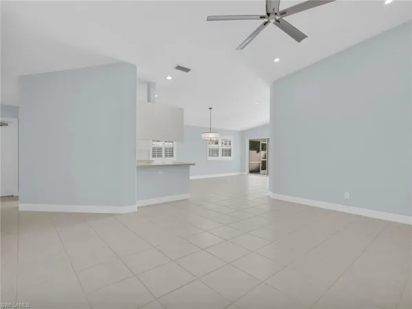 an empty room with kitchen view and a window