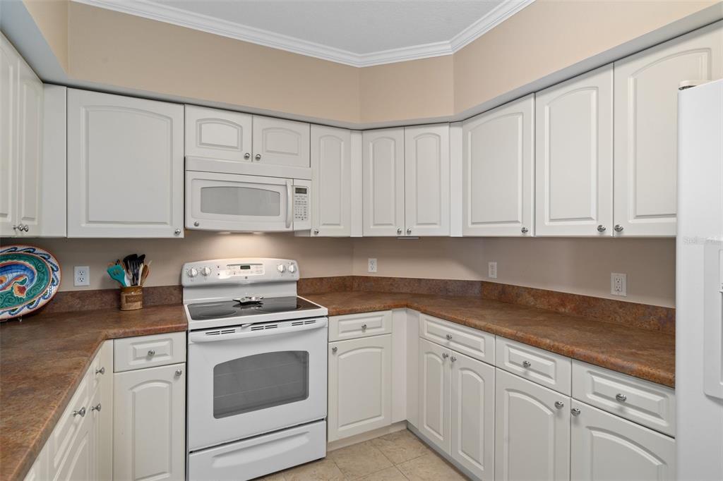 4516 Seagull Drive, Unit 810 New Port Richey, FL 34652 - Photo 29 of 54 a kitchen with granite countertop white cabinets and white appliances