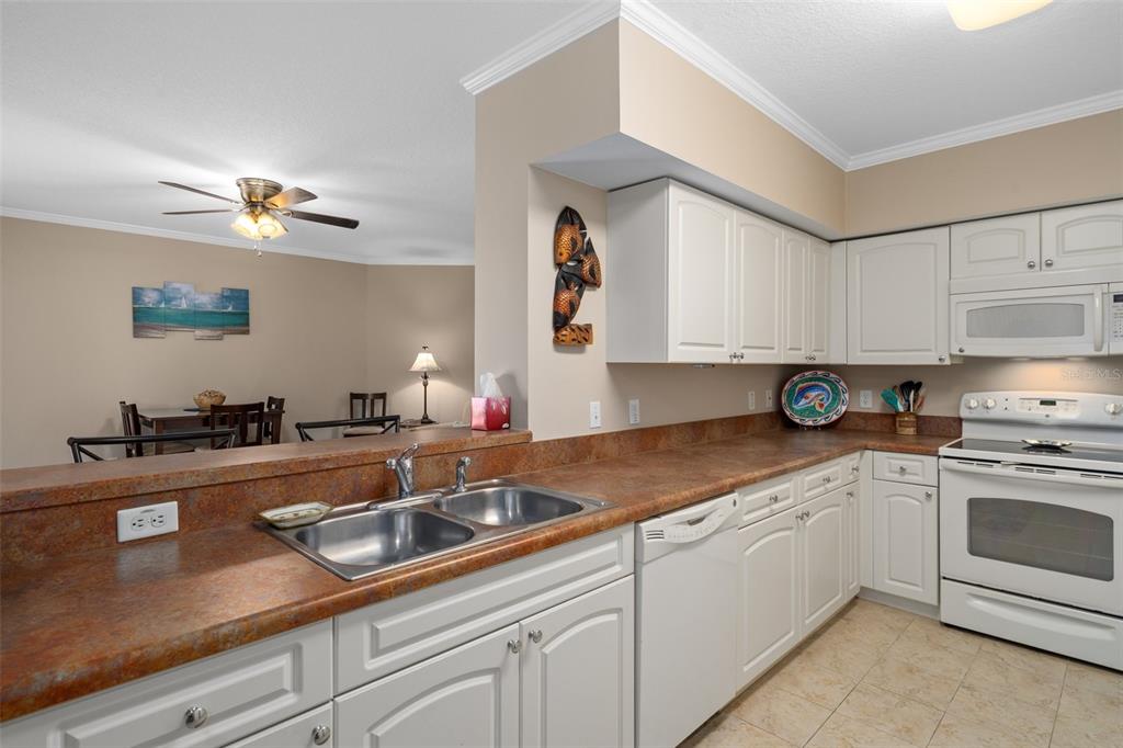 4516 Seagull Drive, Unit 810 New Port Richey, FL 34652 - Photo 31 of 54 a kitchen with a sink dishwasher a stove and white cabinets