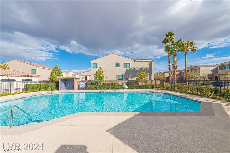 9056 Tony Ridge Avenue Las Vegas, NV 89148 - Photo 28 of 32 A refreshing community pool invites relaxation under the clear blue sky, surrounded by well-maintained landscaping.