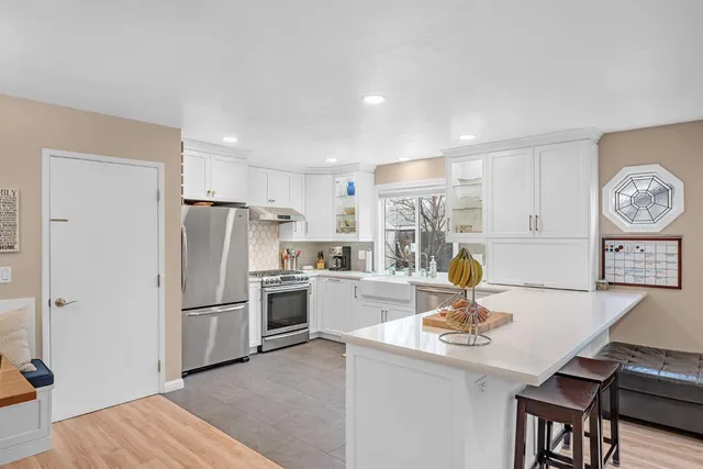 a kitchen with a refrigerator a stove and a dining table with wooden floor
