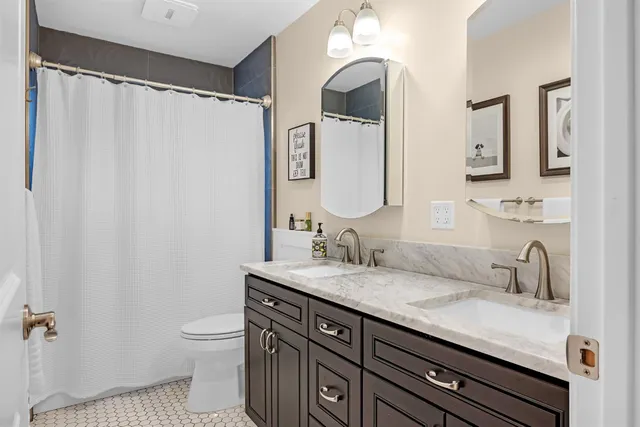 a bathroom with a granite countertop sink a toilet and a mirror