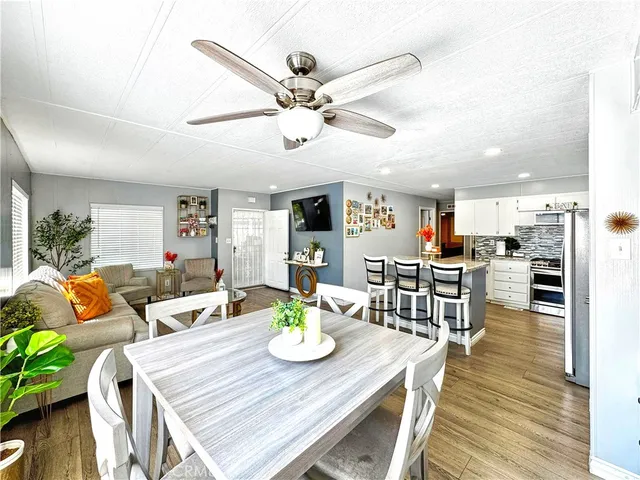 a living room with furniture kitchen view and a wooden floor