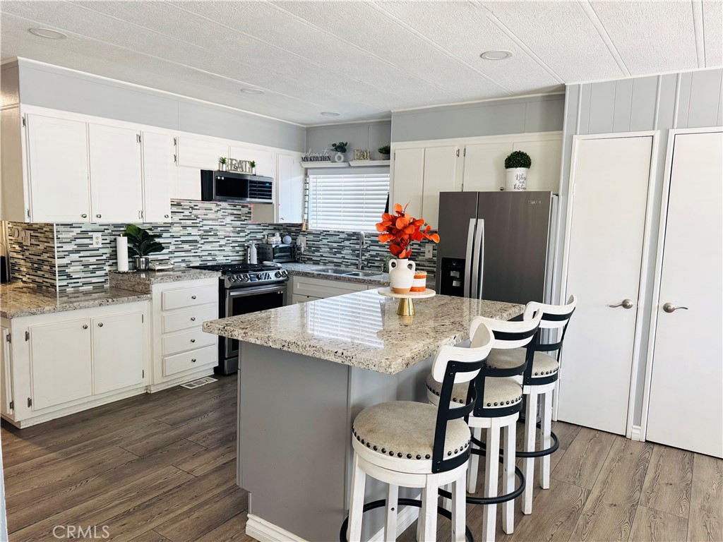 26245 East Baseline Street, Unit 18 Highland, CA 92346 - Photo 8 of 25 a kitchen with stainless steel appliances a dining table chairs refrigerator and microwave