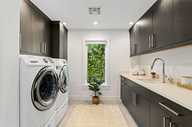 a view of a kitchen with sink washing machine and cabinets