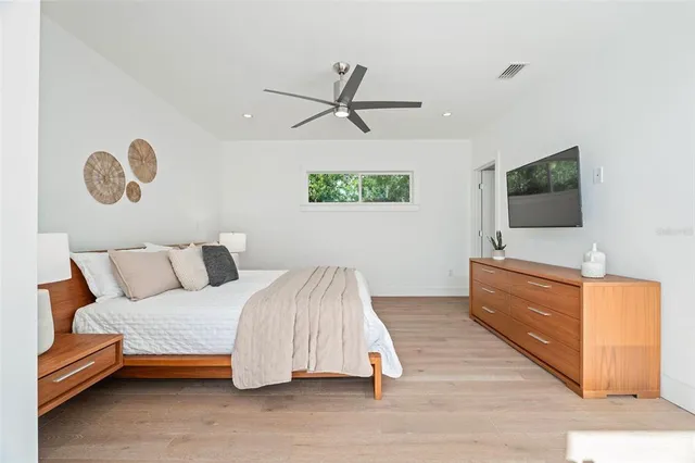 a spacious bedroom with a bed and a flat screen tv