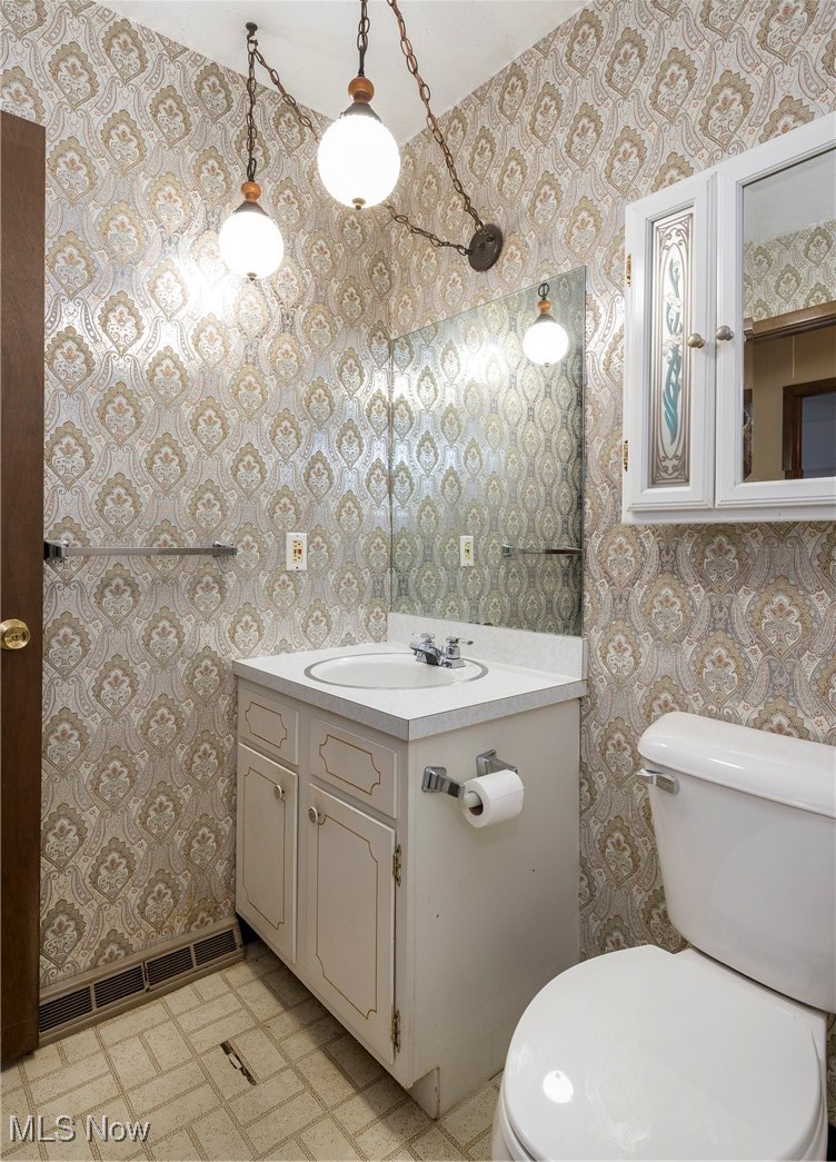 6533 Engle Road Brook Park, OH 44142 - Photo 25 of 38 Half bathroom with wallpapered walls, vanity, tile patterned floors, toilet, and baseboards