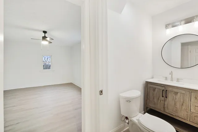 a bathroom with a toilet a sink a mirror and vanity