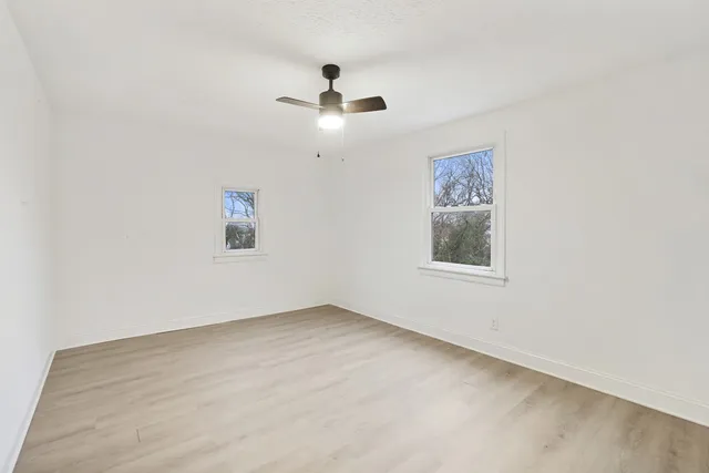 an empty room with a window and a ceiling fan