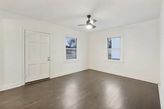 a view of an empty room with a window and wooden floor
