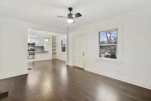 a view of an empty room with a window and wooden floor