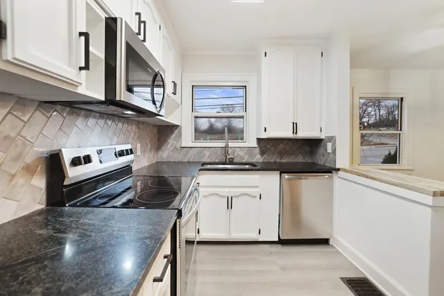 a kitchen with stainless steel appliances granite countertop a stove a sink and a microwave