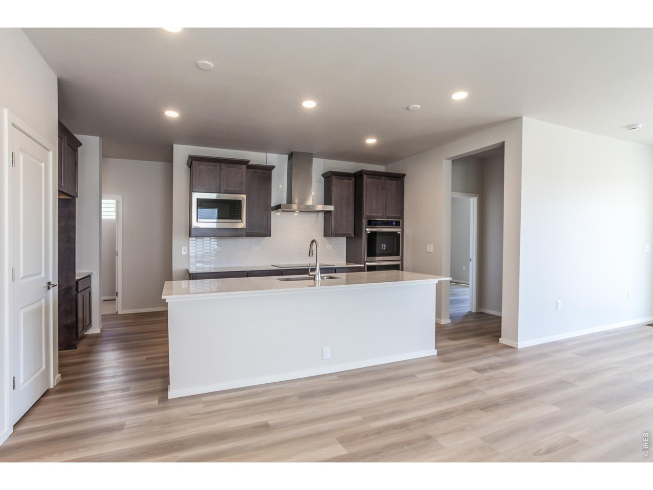 792 Chatter Road Windsor, CO 80550 - Photo 13 of 49 a living room with stainless steel appliances kitchen island granite countertop a refrigerator a sink a stove a microwave and wooden floor