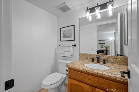 a bathroom with a granite countertop sink a toilet and mirror