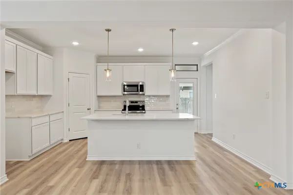 a kitchen with stainless steel appliances white cabinets a sink a stove a refrigerator and island