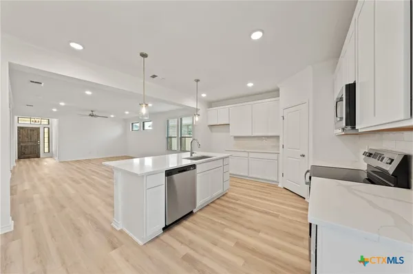a kitchen with white cabinets stainless steel appliances and sink